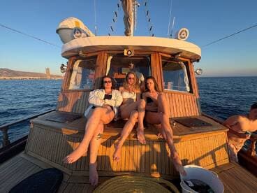 A group of friends relaxes on the deck of a boat during sunset, enjoying the beautiful ocean views — perfect for memorable summer outings.