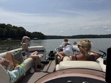 A group enjoys a relaxing day on a pontoon boat, taking in the serene lake views — perfect for family outings and summer fun.