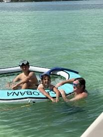 A joyful moment captured with kids enjoying a swim on an inflatable in clear waters — perfect for family fun and summer adventures.