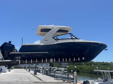 A sleek speedboat is showcased on a lift at the dock, highlighting its elegant design against a clear blue sky — perfect for water adventures.