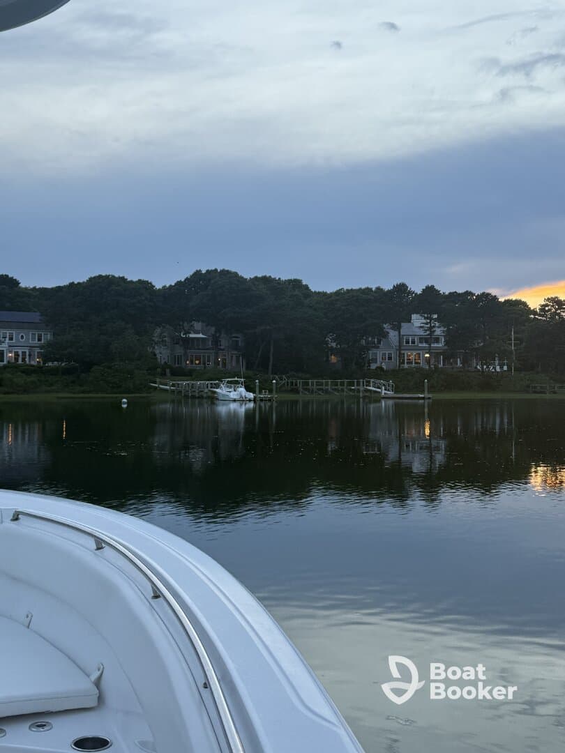 A serene view of a boat's bow with a picturesque waterfront and homes in the background, perfect for showcasing tranquil boating experiences.