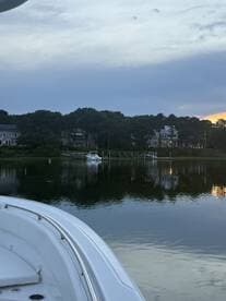 A serene view of a boat's bow with a picturesque waterfront and homes in the background, perfect for showcasing tranquil boating experiences.