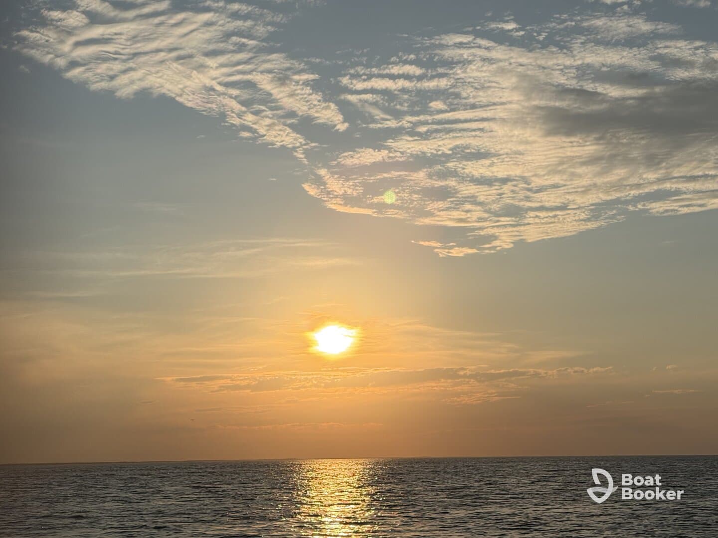 A serene sunset over the ocean, reflecting golden hues on the water's surface — a perfect backdrop for evening boat cruises.