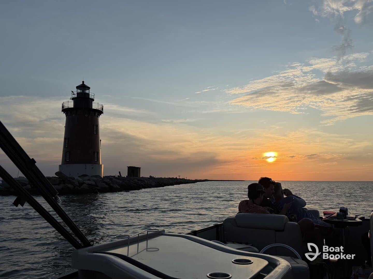 A group enjoys a picturesque sunset view near a lighthouse, creating a perfect backdrop for memorable moments on the water.