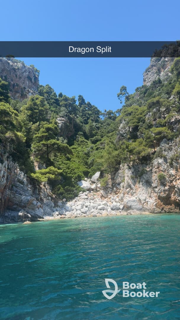 A stunning view of Dragon Split, showcasing lush greenery and rocky cliffs against crystal-clear waters — a perfect destination for boat tours and nature lovers.