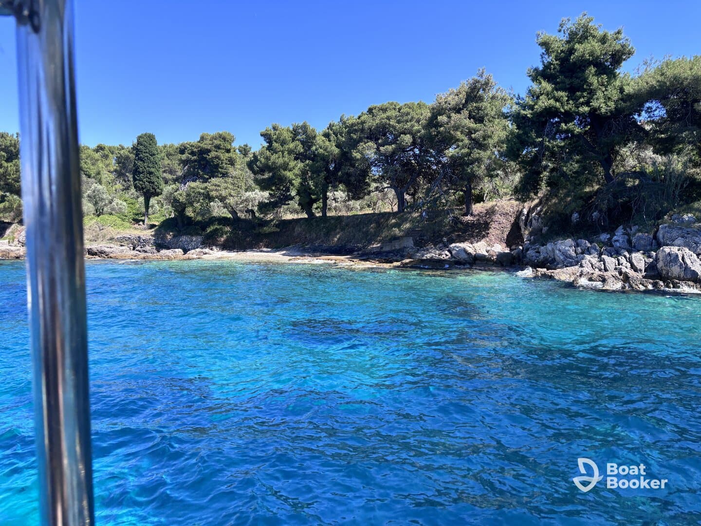 A stunning view of a rocky coastline with lush greenery and crystal-clear turquoise waters, perfect for showcasing the beauty of a boating adventure.