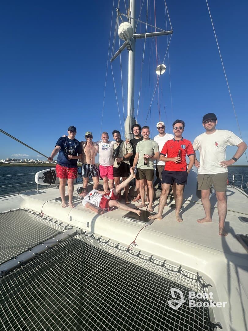 A lively group of friends poses for a photo on the deck of a catamaran, capturing the essence of fun and camaraderie on the water.