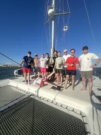A lively group of friends poses for a photo on the deck of a catamaran, capturing the essence of fun and camaraderie on the water.