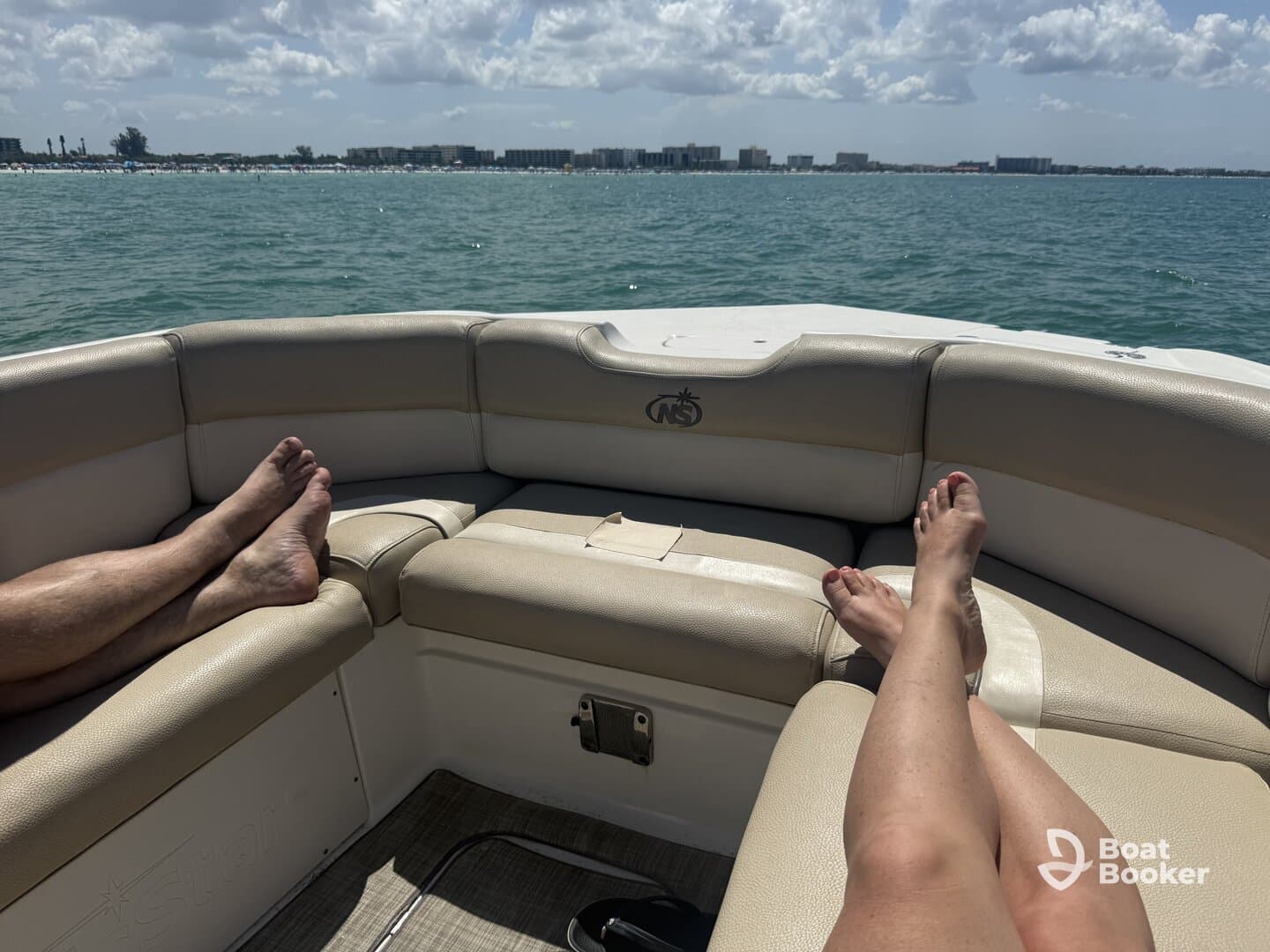 Relaxing on the lounge seating of a boat, with feet up and a scenic view of the water and shoreline — perfect for unwinding on a sunny day.
