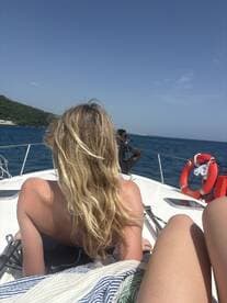 Two friends relax on the bow of a boat under the sun, enjoying a beautiful day on the water — perfect for unwinding and soaking up the scenery.
