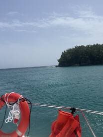 A scenic view from a boat showcasing the tranquil ocean and a lush green coastline, perfect for a relaxing day on the water.