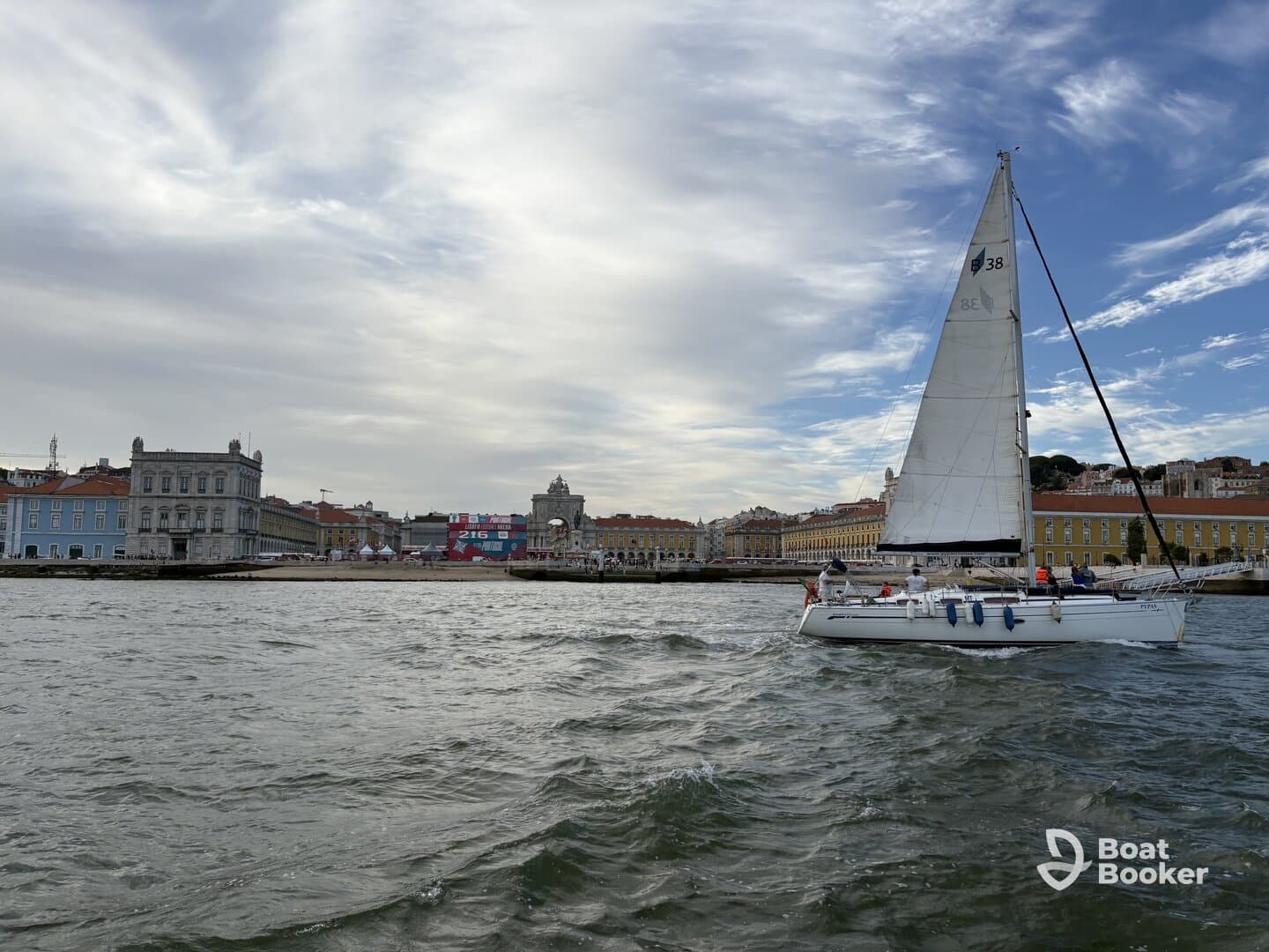 A sailboat glides through the waters of Lisbon, showcasing the vibrant cityscape in the background — a perfect scene for sailing enthusiasts and urban explorers alike.