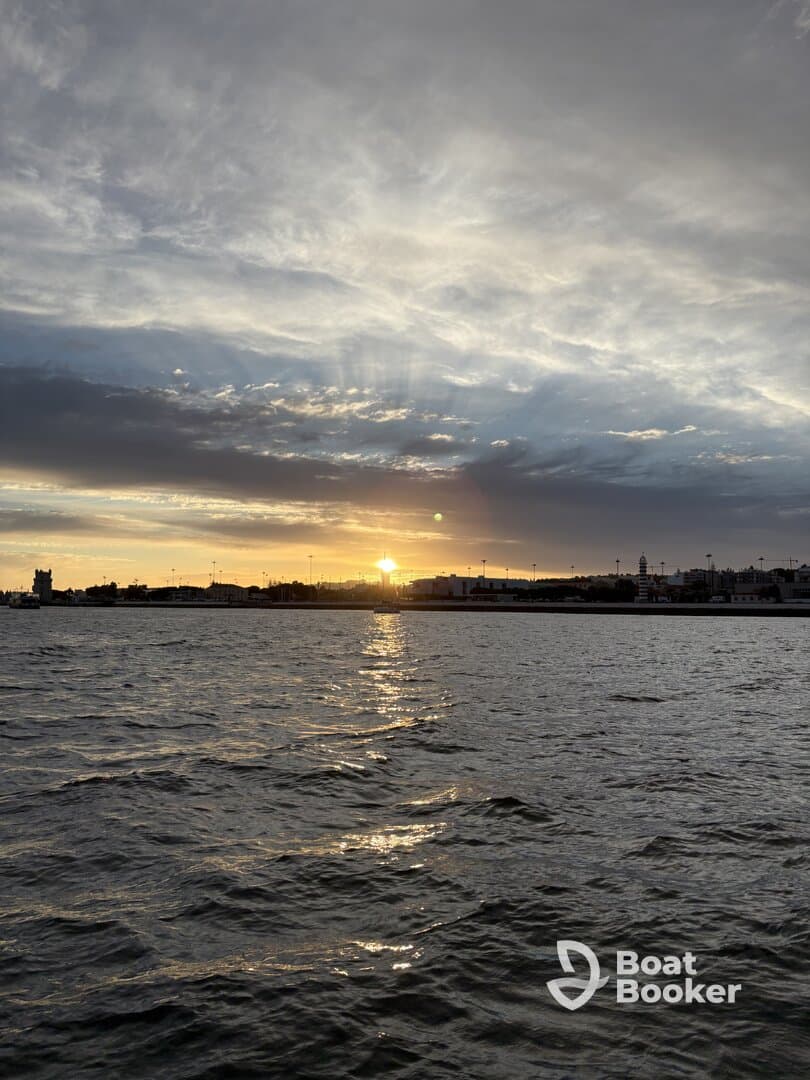 A stunning sunset casts golden reflections on the water, creating a picturesque scene along the coastline — perfect for capturing the beauty of evening boat trips.