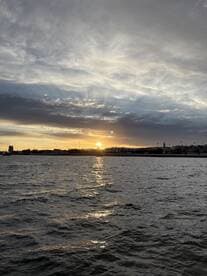 A stunning sunset casts golden reflections on the water, creating a picturesque scene along the coastline — perfect for capturing the beauty of evening boat trips.