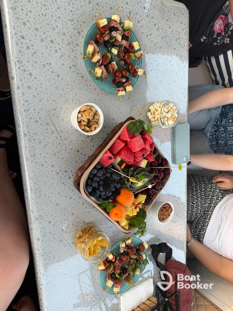 A beautifully arranged spread of fruits, snacks, and charcuterie on a boat table, perfect for enjoying refreshments while cruising on the water.