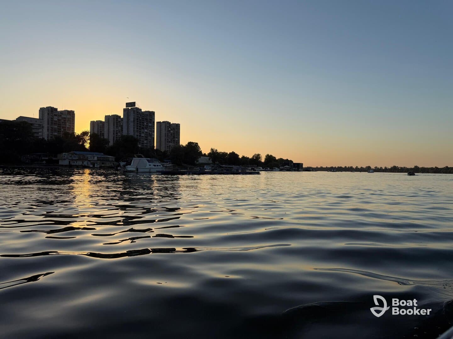 A serene sunset view over the water, showcasing a city skyline and reflecting golden hues — perfect for capturing the beauty of urban waterfronts.