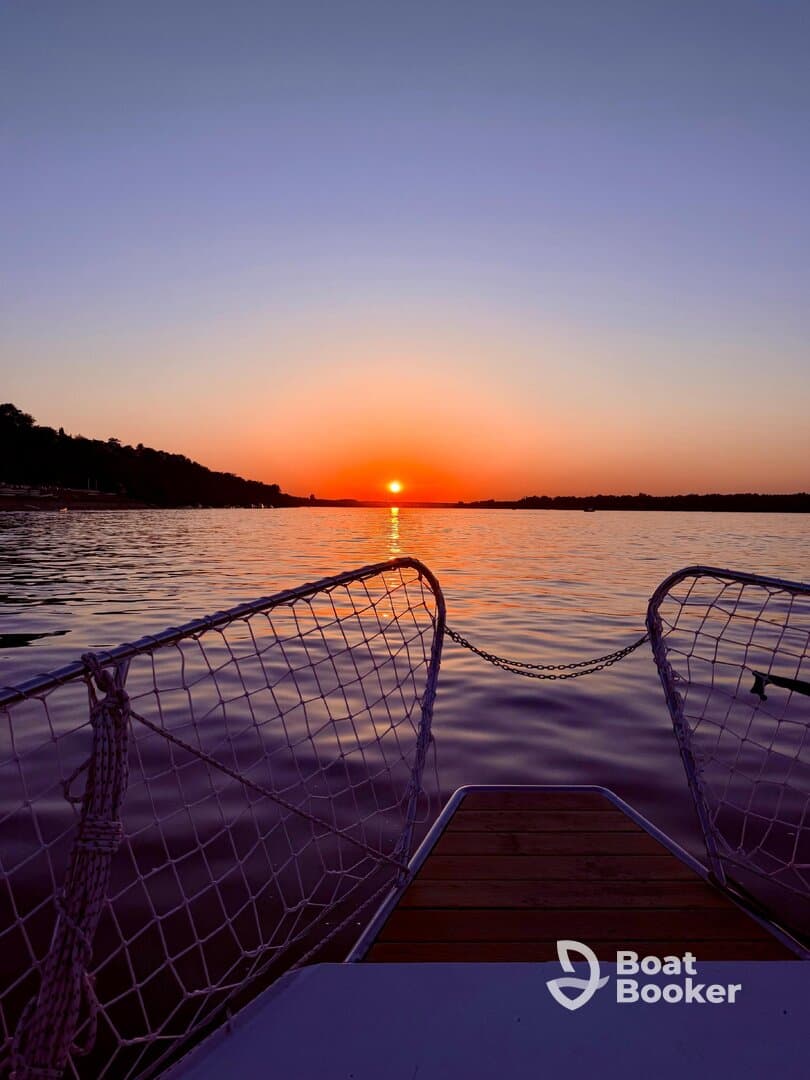 A stunning sunset view from the bow of a boat, showcasing tranquil waters and a vibrant sky — perfect for evening cruises.