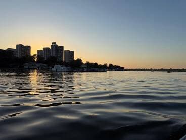 A serene sunset view over the water, showcasing a city skyline and reflecting golden hues — perfect for capturing the beauty of urban waterfronts.