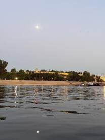 A serene evening view of the moon reflecting on the water, with a picturesque landmark in the background — perfect for capturing the beauty of a tranquil night on the water.