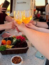 A group toasts with cocktails while enjoying a vibrant spread of fresh fruit and snacks aboard a boat, capturing the essence of a festive celebration on the water.