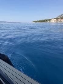 A serene view of a boat gliding through crystal-clear waters, showcasing the beautiful coastline and tranquil surroundings — perfect for exploring the stunning landscapes of the sea.