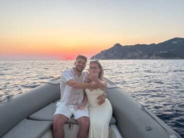 A couple enjoys a romantic moment on a boat at sunset, capturing the essence of love and adventure on the water.