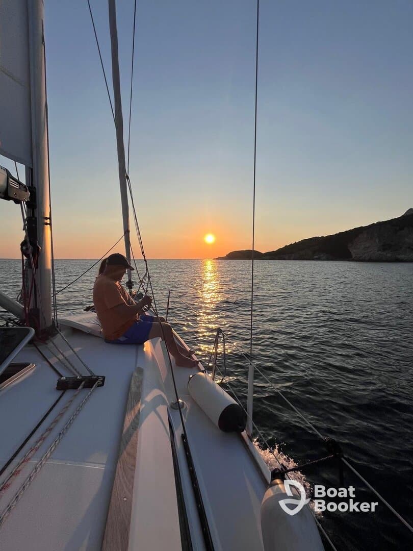 A serene moment as a person enjoys the sunset while sailing, capturing the essence of relaxation on the water.