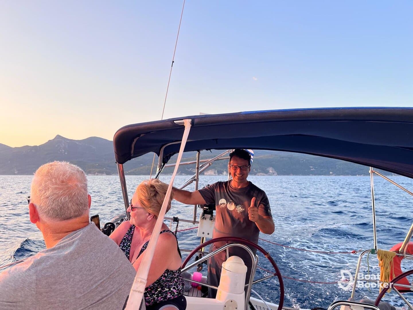 A cheerful group enjoys a sailing experience, with one member giving a thumbs up while navigating the beautiful waters — perfect for memorable adventures on the sea.