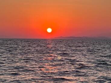 A stunning sunset over the ocean, casting vibrant colors across the water — a perfect backdrop for evening boat cruises.