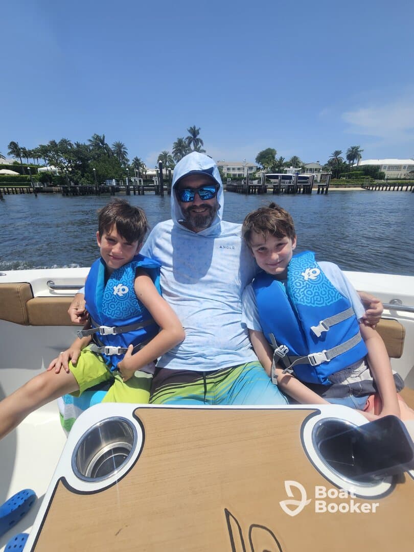 A father enjoys a sunny day on the boat with his two sons, all wearing life jackets, capturing a perfect family moment on the water.