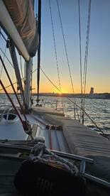 A stunning sunset view from the deck of a sailboat, showcasing the tranquil waters and distant shoreline — perfect for romantic evening cruises.