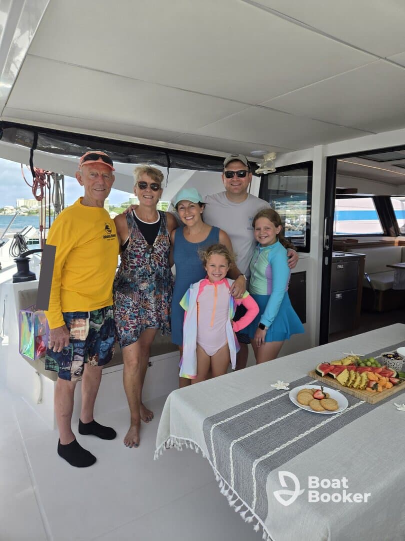A joyful family poses together inside a boat, showcasing a delightful spread of fruits and snacks — perfect for memorable gatherings on the water.