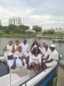 A lively group of friends dressed in white enjoys a fun day on the boat, perfect for celebrations and gatherings on the water.