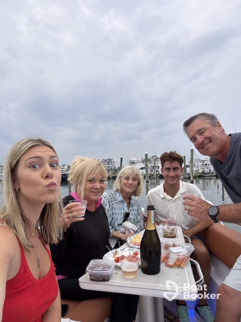 A cheerful group enjoys a boat party with cocktails and delicious food, capturing the essence of fun and celebration on the water.