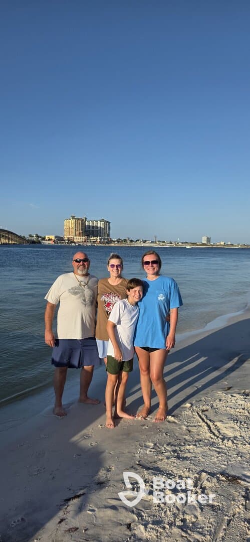 A cheerful family poses for a photo on the beach, capturing a memorable moment during their seaside adventure.