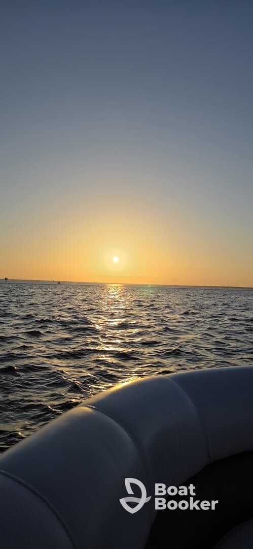 A serene sunset view from the edge of a boat, capturing the tranquil waters and the golden horizon — perfect for evening cruises.