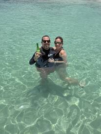 A couple enjoys a refreshing drink while swimming in crystal-clear waters, capturing the essence of a perfect day on the water.