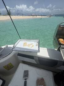 A grill setup on a boat with food prepared, overlooking a beautiful beach scene — perfect for a day of cooking and enjoying the sun.
