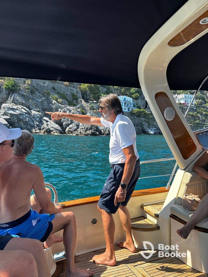 A group of guests aboard a boat enjoy the scenic views, with one person pointing out an interesting sight along the coastline. Perfect for capturing memorable moments on the water.