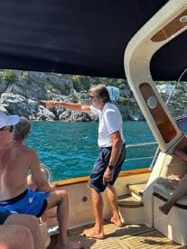 A group of guests aboard a boat enjoy the scenic views, with one person pointing out an interesting sight along the coastline. Perfect for capturing memorable moments on the water.