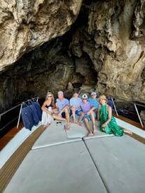 A cheerful group poses for a photo aboard a boat inside a stunning cave, capturing a memorable moment during their adventure.