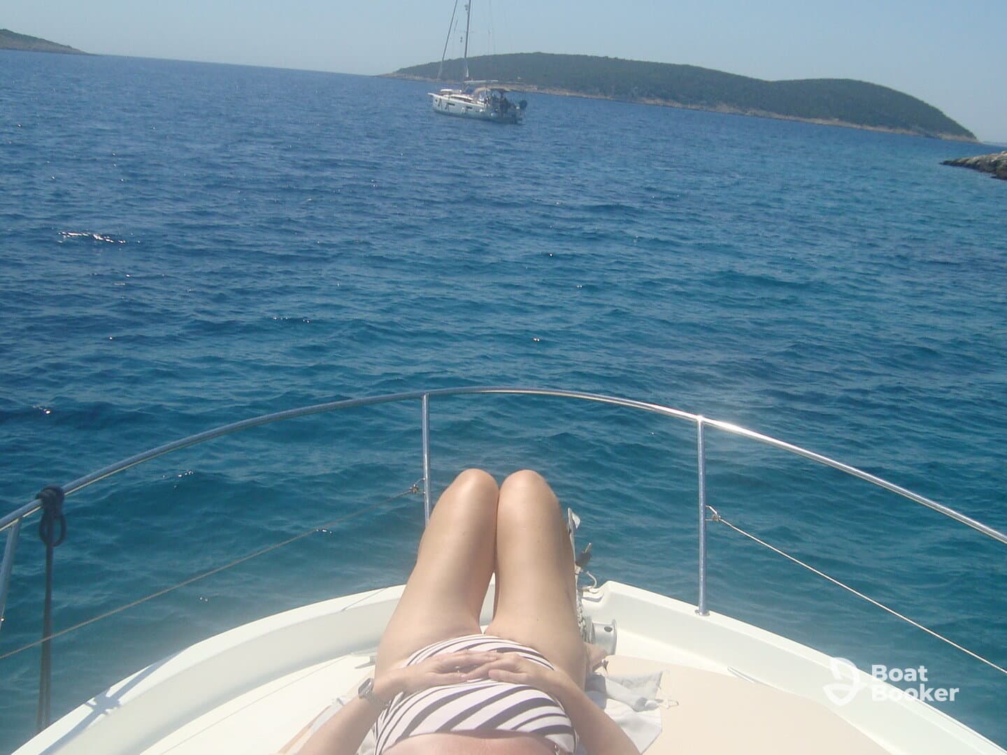 A person relaxes on the deck of a boat, enjoying the sun and the serene ocean view — a perfect moment for relaxation on the water.