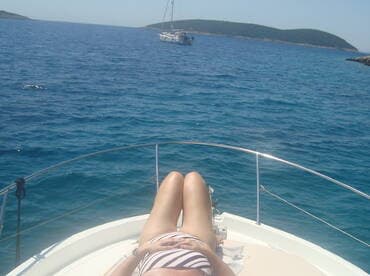 A person relaxes on the deck of a boat, enjoying the sun and the serene ocean view — a perfect moment for relaxation on the water.
