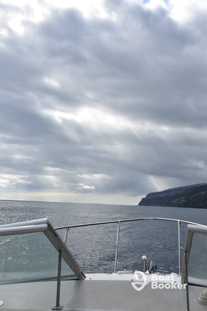 A serene view from the bow of a boat, showcasing the expansive ocean and distant coastline under a cloudy sky — perfect for exploring coastal waters.