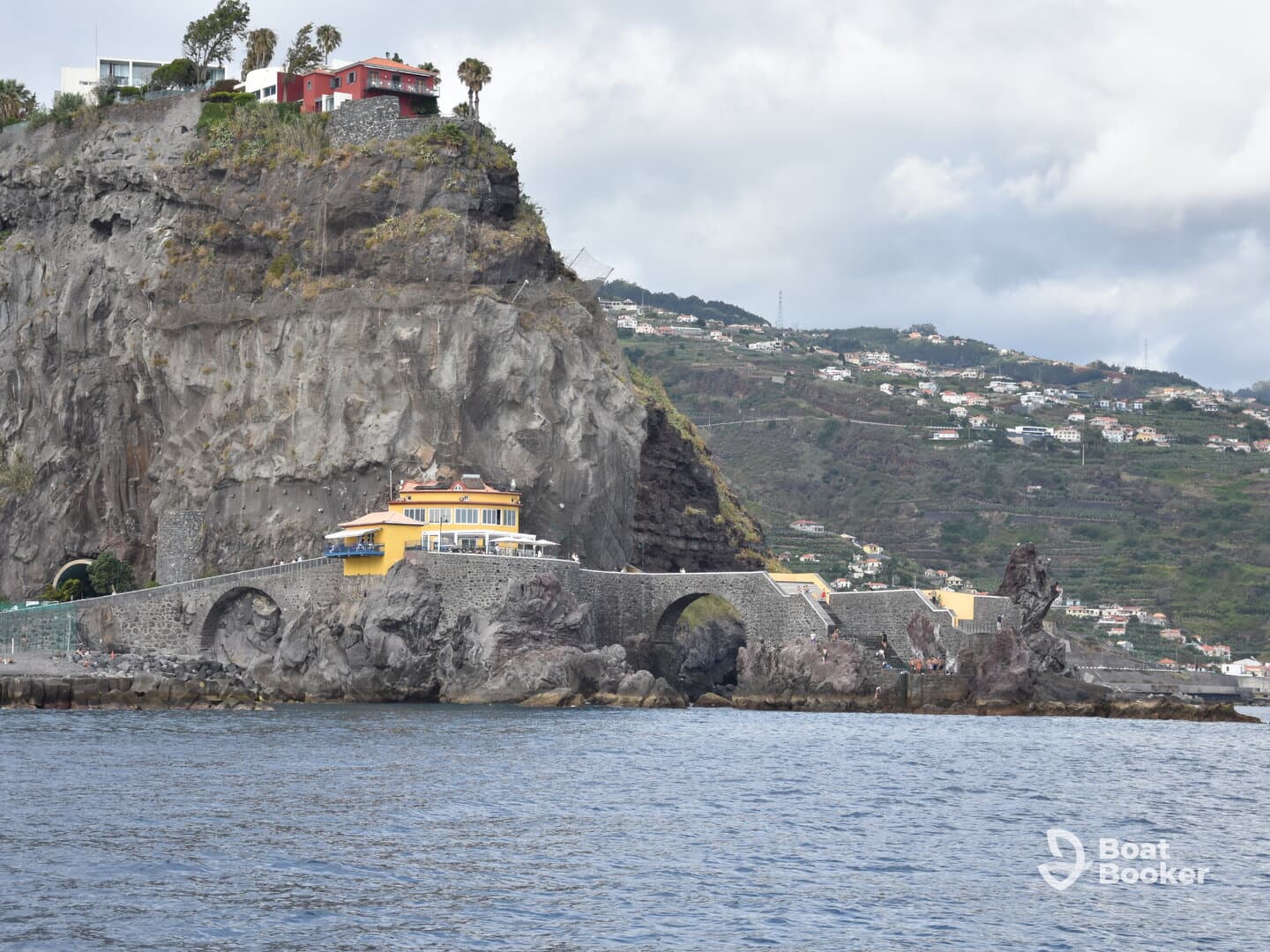 A picturesque view of a coastal landmark with a vibrant yellow building perched on the rocky cliffs, showcasing the stunning landscape of Madeira.