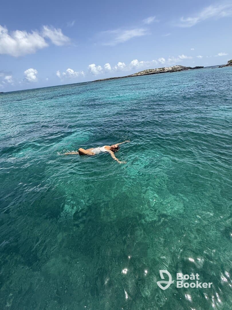 A woman enjoys a refreshing swim in the crystal-clear waters, showcasing the beauty of a tropical paradise — perfect for adventure seekers and beach lovers.