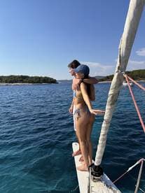 A couple enjoys a romantic moment on the bow of a sailboat, embracing the ocean breeze and stunning views — perfect for adventure seekers and lovers alike.