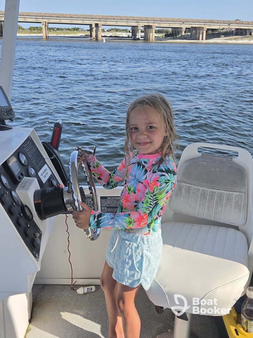 A young girl joyfully steers a boat, showcasing the excitement of learning to navigate on the water — a perfect moment for family boating adventures.