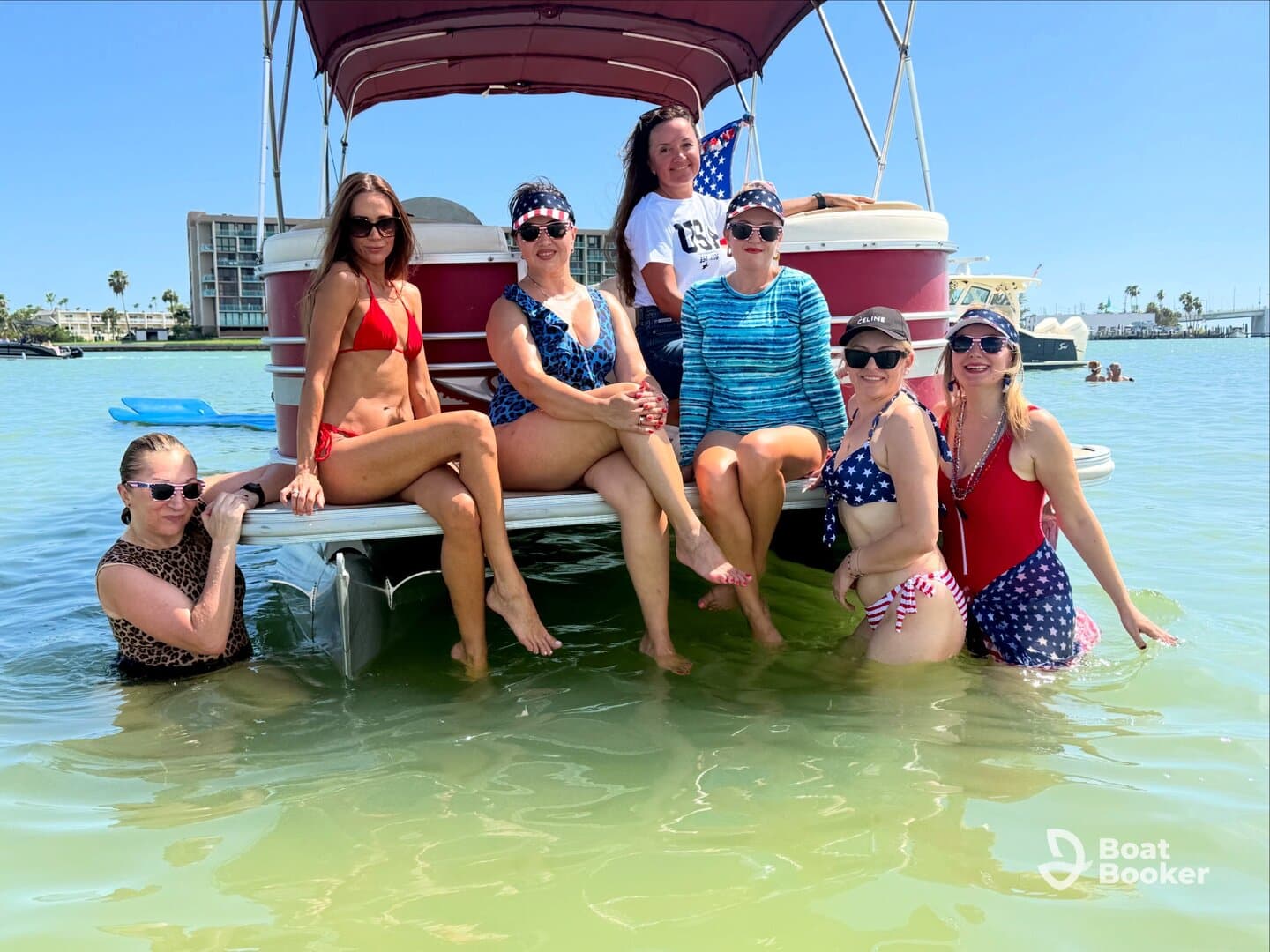 A fun group of friends enjoys a sunny day on a pontoon boat, splashing in the water and celebrating together — perfect for summer outings and memorable gatherings.