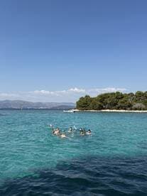 A lively group enjoys a refreshing swim in crystal-clear waters, showcasing the perfect summer day on the beach.